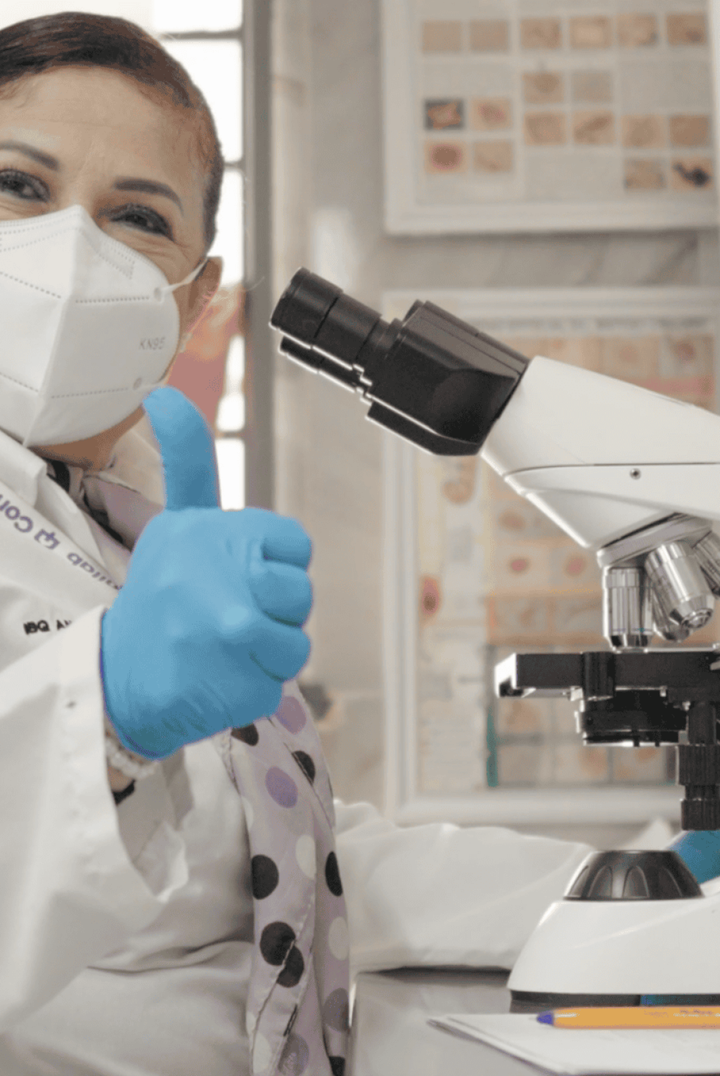 Científica en laboratorio usando microscopio y equipo de protección.