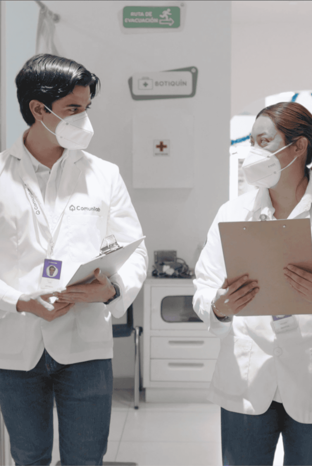 Dos profesionales de salud en comunicación en un entorno clínico con mascarillas.